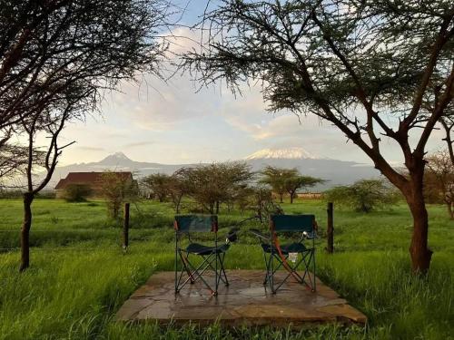 dwa krzesła siedzące na kamiennym stole na polu w obiekcie Amboseli Cultural Camping w mieście Amboseli