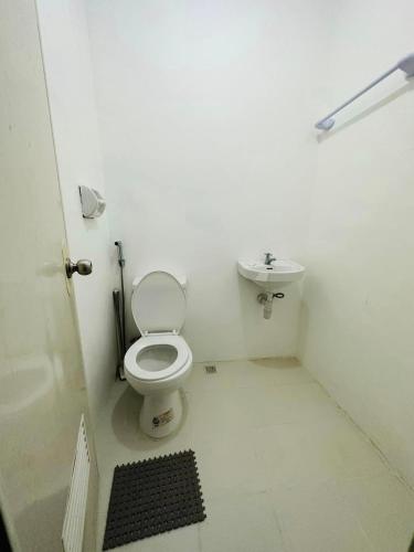 een witte badkamer met een toilet en een wastafel bij Bachelorette Rental in Ormoc