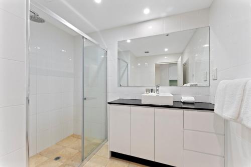 Baño blanco con lavabo y espejo en APX Darling Harbour, en Sídney