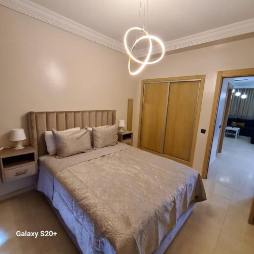 Schlafzimmer mit einem Bett und einem Kronleuchter in der Unterkunft Appartement complexe dream hills in Tangier