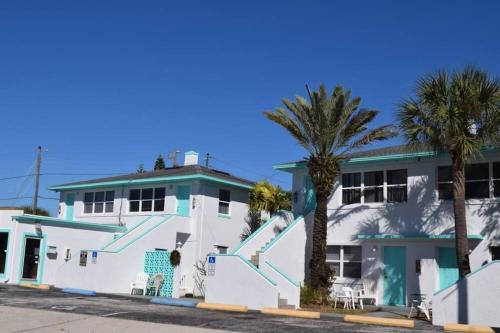 un edificio blanco con palmeras delante en Private Large Studio 19-Directly Across from Beach en St Pete Beach
