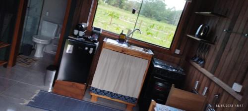 cocina con fregadero, nevera y ventana en Arandu Chalés en Imbituba