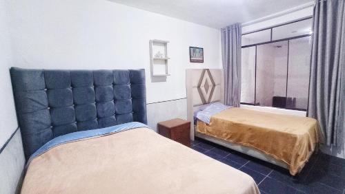 1 dormitorio con 2 camas y cabecero azul en Dpto 1er Nivel Punta hermosa 3hab, wifi, tv, parrilla, en Punta Hermosa