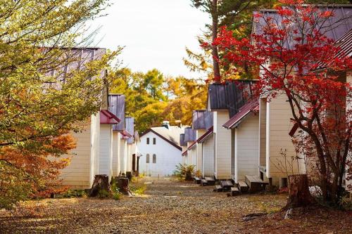 a row of white buildings with trees in the background at Shinei Kiyosato Campsite - Vacation STAY 42212v in Hokuto