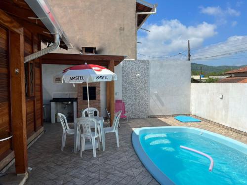 un patio con mesa, sombrilla y piscina en Casa do Kélvio, en Penha