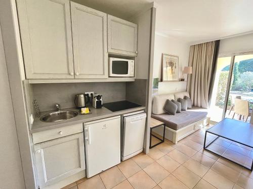 馬勒莫爾的住宿－Appartement Golf de Pont Royal，厨房配有白色橱柜、桌子和沙发