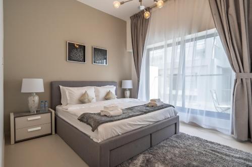 a bedroom with a bed and a large window at Al Meydan - Prime Views 1BR in Al Meydan in Dubai