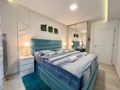 a bedroom with a blue bed and a mirror at Apartmani SLEEP&JOY in Zlatibor