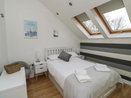 a bedroom with two beds and a desk and two windows at Little Rondeval in Totnes