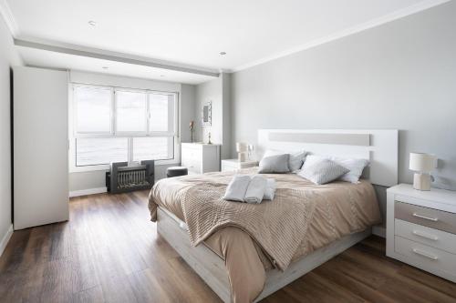 a white bedroom with a large bed and a window at Amanecer Cantábrico in Gijón