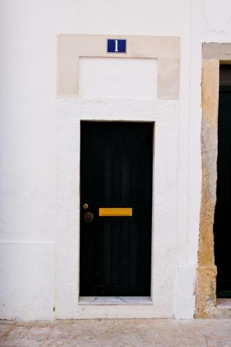 a black door with a yellow sign on it at Pequeno Hostel in Lisbon