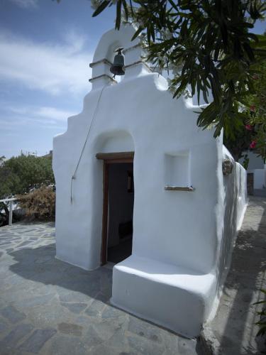 a white building with a door and a tree at Semeli Hotel Mykonos in Mýkonos City