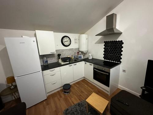 een keuken met witte kasten en een klok aan de muur bij 10B sunset park homes in Brackley