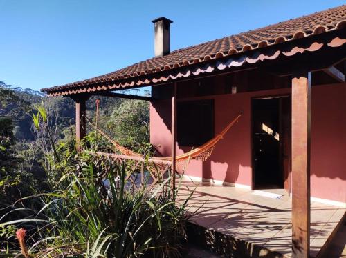 una casa roja con una hamaca fuera de ella en CHALÉ vista linda- VISCONDE DE MAUA, en Bocaina de Minas