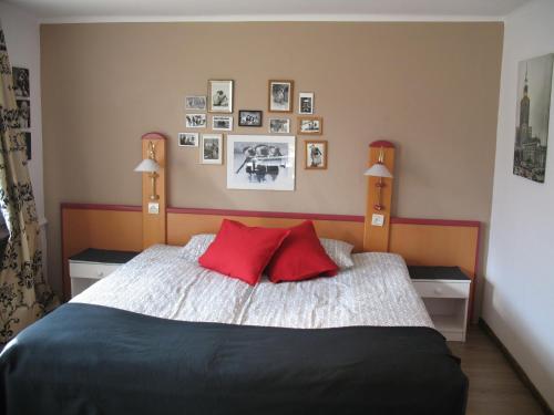a bedroom with a bed with red pillows and pictures on the wall at Willa Pod Aniołem - Pokoje Gościnne & Apartamenty z widokiem na góry in Szczyrk