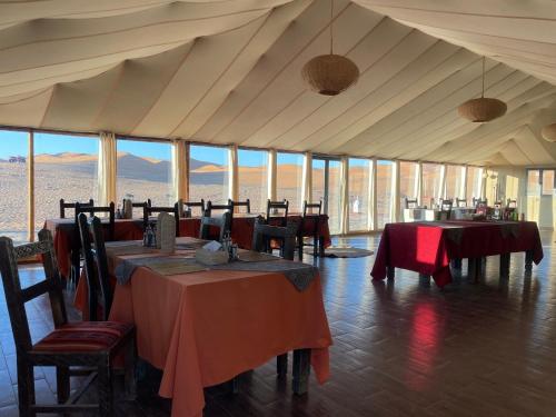 a dining room with tables and chairs and windows at Luxury Camp Of Dar Morocco in Merzouga