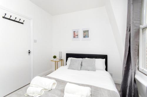 a white bedroom with a bed with white sheets and pillows at Strand Central Apartments in London