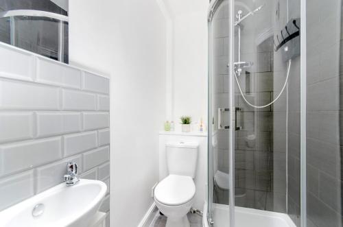 a white bathroom with a toilet and a shower at Strand Central Apartments in London