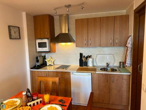 a kitchen with wooden cabinets and a sink and a table at Monte Oiz con wifi y parking gratis in Sierra Nevada