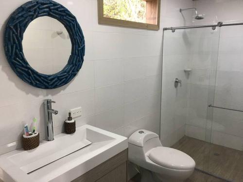 a bathroom with a toilet and a sink and a mirror at La Casita Azul Boutique Villa in Providencia