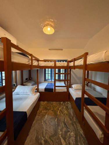 Zimmer mit 3 Etagenbetten und einem Kronleuchter in der Unterkunft The Barefoot Varkala in Varkala