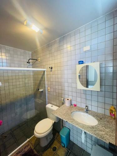 een badkamer met een toilet, een wastafel en een douche bij Condomínio Rochas do Mar in Barra de São Miguel