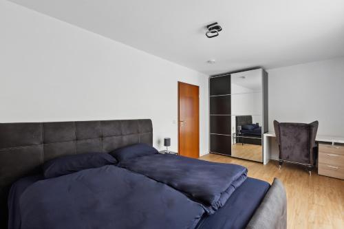 1 dormitorio con 1 cama azul grande y escritorio en Eindrucksvolle Zwei-Zimmer-Wohnung mit Balkon und großer Küche en Leipzig