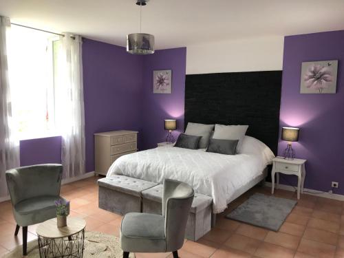a bedroom with purple walls and a bed and chairs at Chambre d'hôte Lavande - Le soleil des Cévennes in Saint-Jean-du-Gard