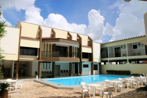 - un bâtiment avec une piscine et des chaises blanches dans l'établissement Veneza Plaza Hotel, à Gurupi