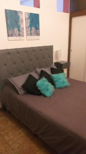 a bed with two green pillows on top of it at departamento del centro in La Falda