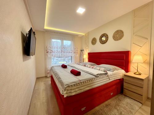 a bedroom with a red bed and a window at Apartmani SLEEP&JOY in Zlatibor