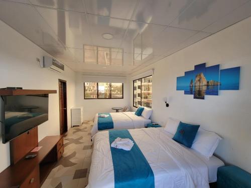 a bedroom with two beds and a flat screen tv at Hostal Gosén in Puerto Baquerizo Moreno