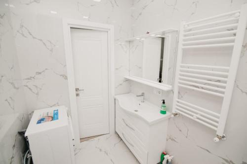 a white bathroom with a sink and a mirror at Apartments in the center in Chişinău