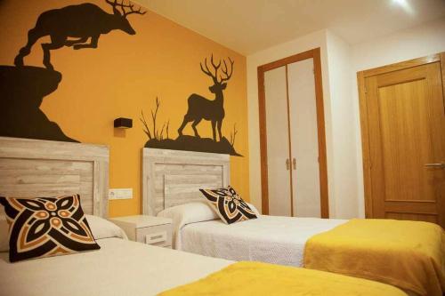ein Hotelzimmer mit 2 Betten und einer Hirschwand darauf in der Unterkunft Cumbres De Los Picos Apartamento Rebecos in Poo de Cabrales