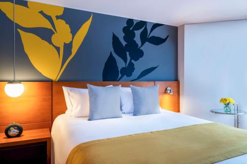 ein Schlafzimmer mit einem Bett mit einer blauen und gelben Wand in der Unterkunft Avani Royal Zona T Bogotá Hotel (previously NH Bogotá Boheme Royal) in Bogotá