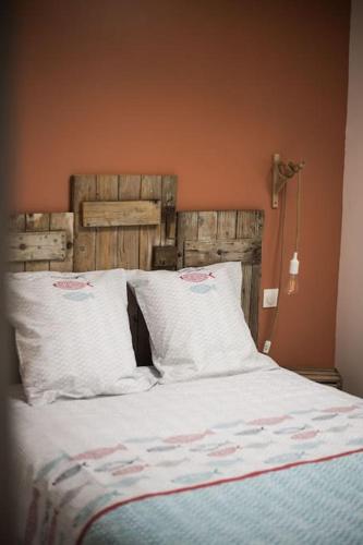 un lit avec des oreillers blancs et une tête de lit en bois dans l'établissement Maupiti proche Etretat et Fécamp, à Vattetot-sur-Mer