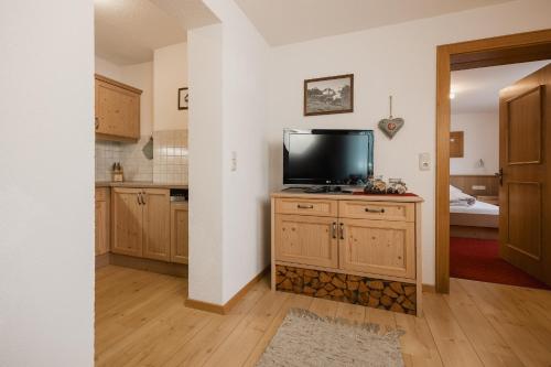 a kitchen with a flat screen tv on a wooden cabinet at Apart Tyrol in Serfaus