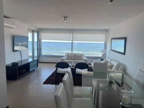 a living room with white furniture and a view of the ocean at Edificio Calypso - Primera línea al Mar in Punta del Este