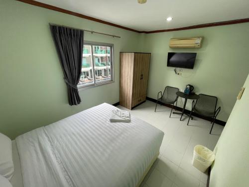 a bedroom with a bed and a table and a window at Omaya GuestHouse in Patong Beach