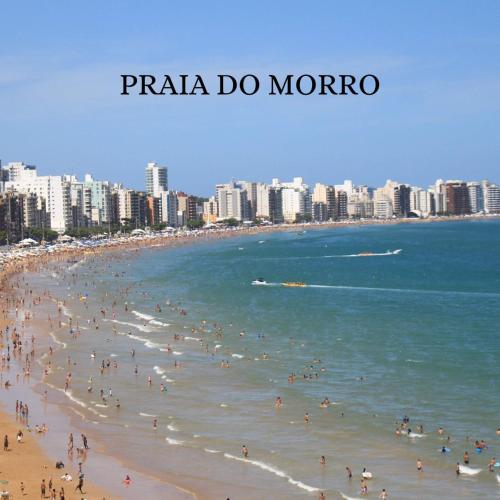 a group of people on a beach in the ocean at Apartamento Praia do Morro in Guarapari