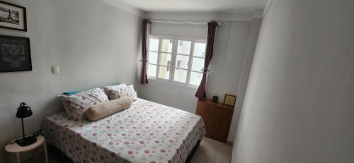 a small bedroom with a bed and a window at Lindo Apartamento compacto na quadra da praia in Santos