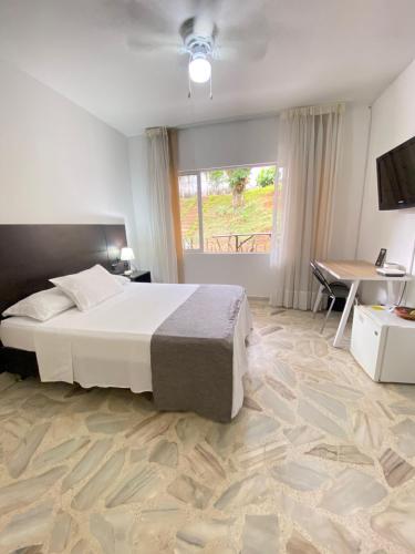 a bedroom with a bed and a desk and a window at Babilla Suites in Cali