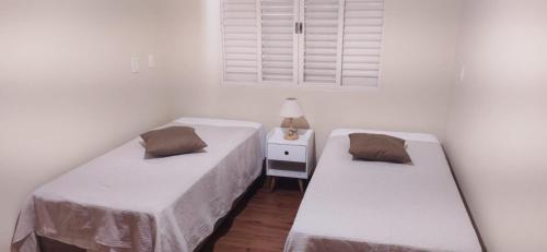 Duas camas num pequeno quarto com paredes brancas em Chalet Rustico da Elena com Sauna y Jacuzzi Unicep em São Carlos