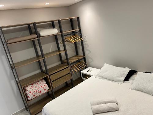 um quarto com uma cama e uma estante de livros em Residencial Atalaia - Praia do Gravatá - Beto Carrero World em Navegantes