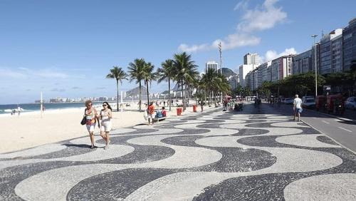 La gente caminando en una playa con una acera giratoria en Flat Copacabana quadra da praia 907, en Río de Janeiro