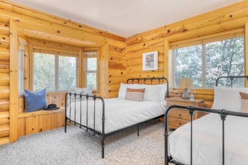 Duas camas num quarto com paredes e janelas de madeira em Tanglewood by AvantStay 10mins to Bear Mountain Contemporary Hillside Cabin em Big Bear Lake