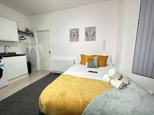 a white bedroom with a large bed with yellow blanket at Charming & Cosy Studio Retreat in Kidderminster in Kidderminster