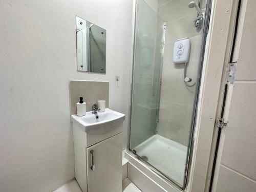 a white bathroom with a sink and a shower at Charming & Cosy Studio Retreat in Kidderminster in Kidderminster