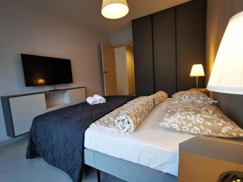 a bedroom with a large bed with a tv on the wall at Apolonia apartamenty I - SPA in Dziwnów