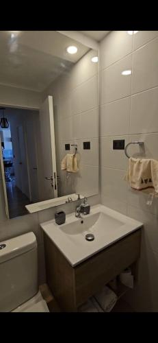 a bathroom with a sink and a toilet and a mirror at Depto Carvajal in Santiago